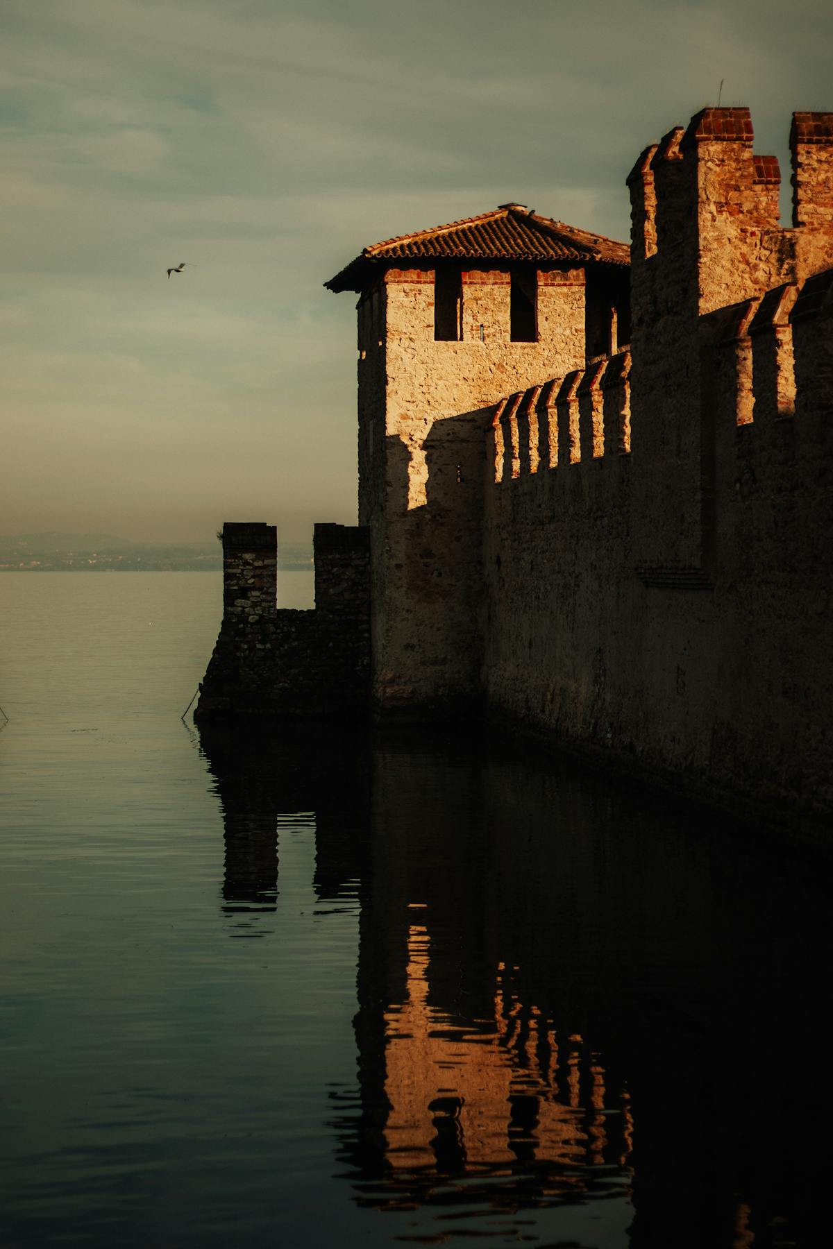 The Scaliger castle and fortified harbour at Sirmione seen from across the water at dusk