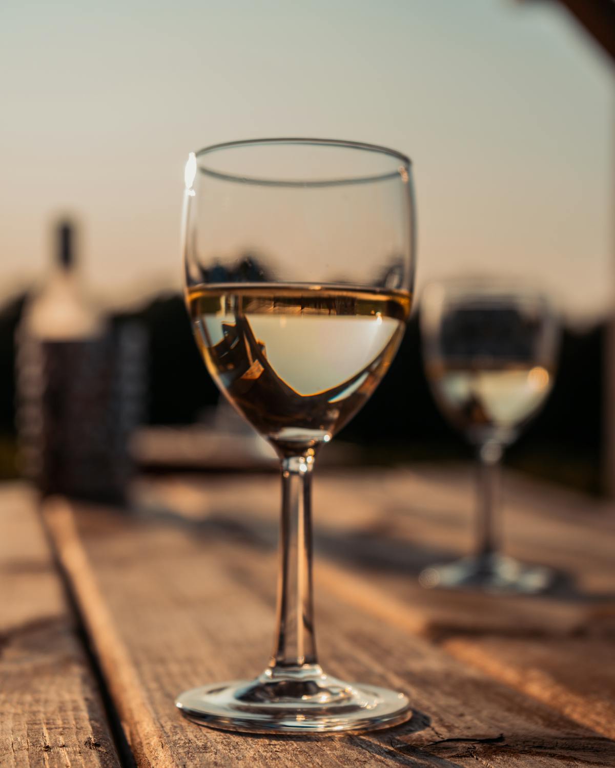 A glass of pale gold Lugana wine on a vineyard stone wall in late afternoon light