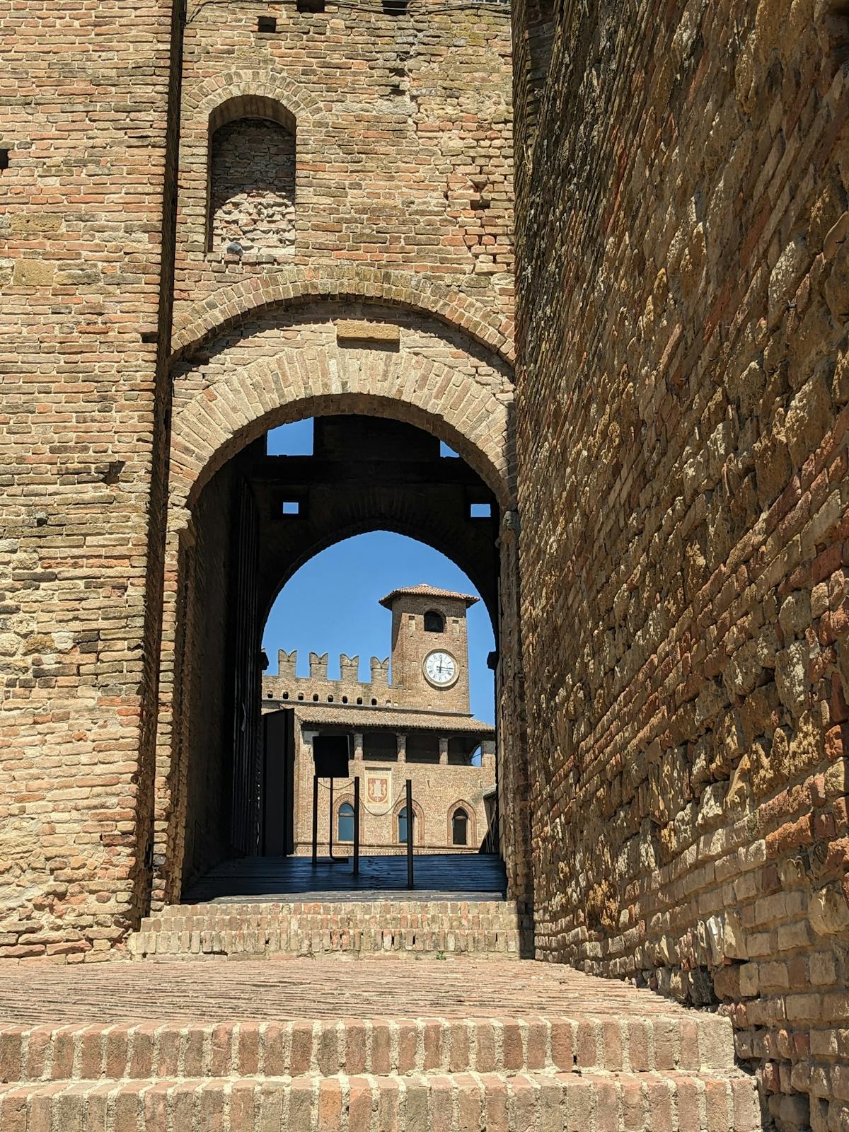 Stone gateway of the Castello di Padenghe with worn medieval walls and tile roofs