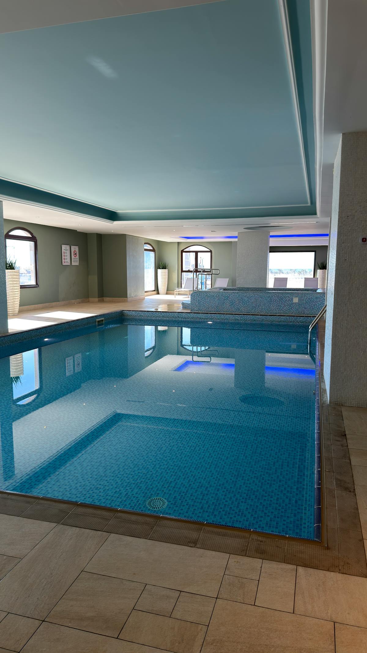 An indoor thermal pool at a southern Lake Garda spa with blue mosaic tiles and arched windows